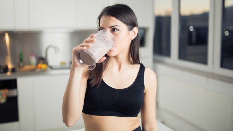 Woman drinking a protein shake post workout, during the anabolic window