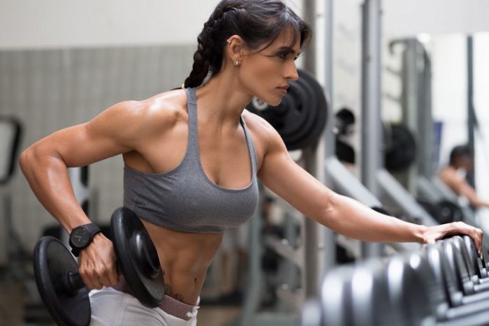 woman doing a chest and arms workout holding a dumbbell