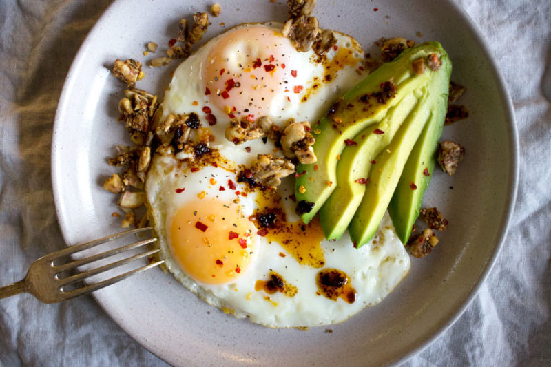 eggs with walnuts, chilli flakes and avocado on a plate for breakfast