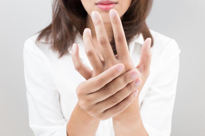 Woman holding her hand to represent hand tingles
